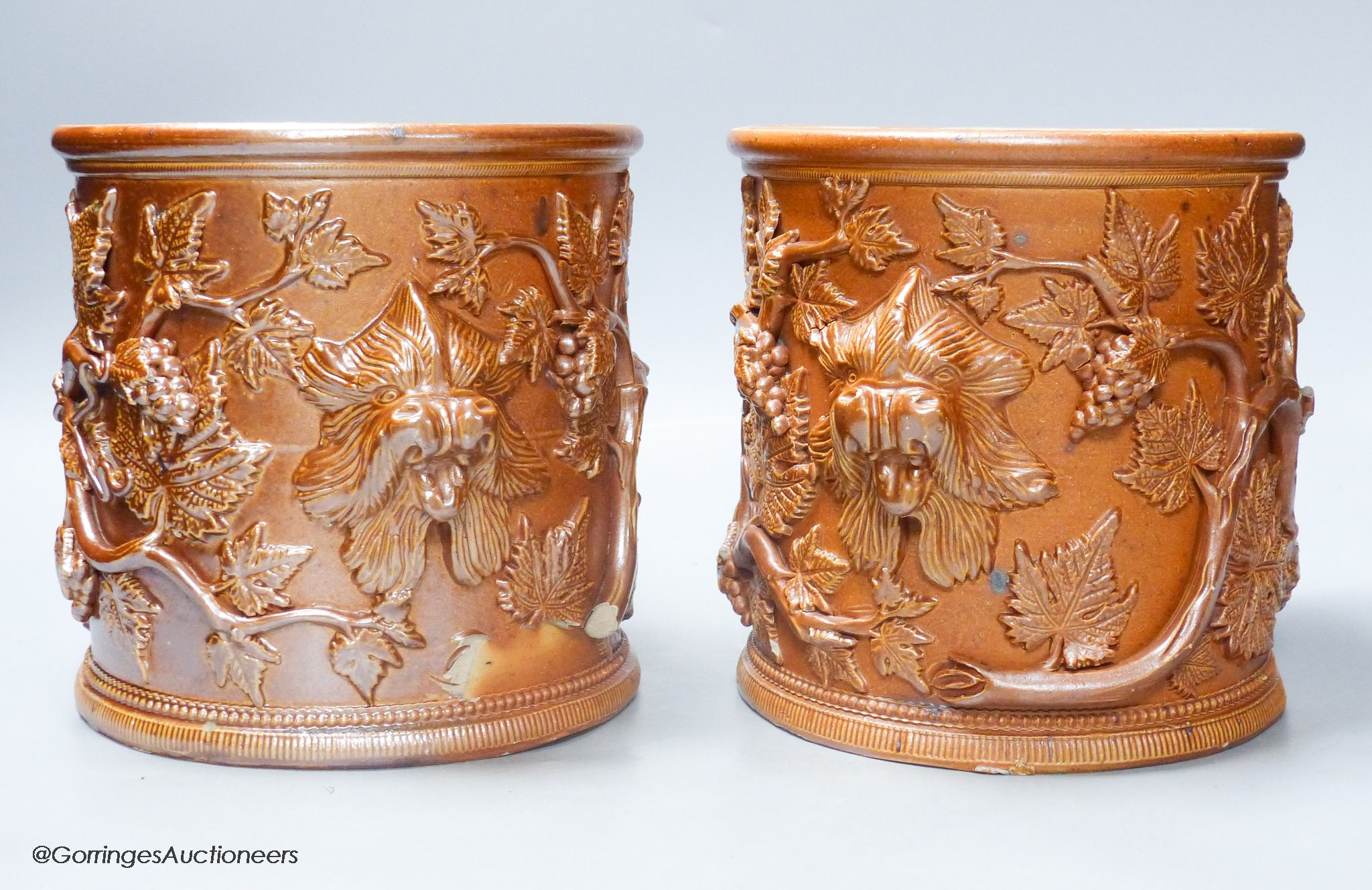 A pair of early 19th century salt glazed stoneware cylindrical pots, relief moulded with grapes and vine leaves